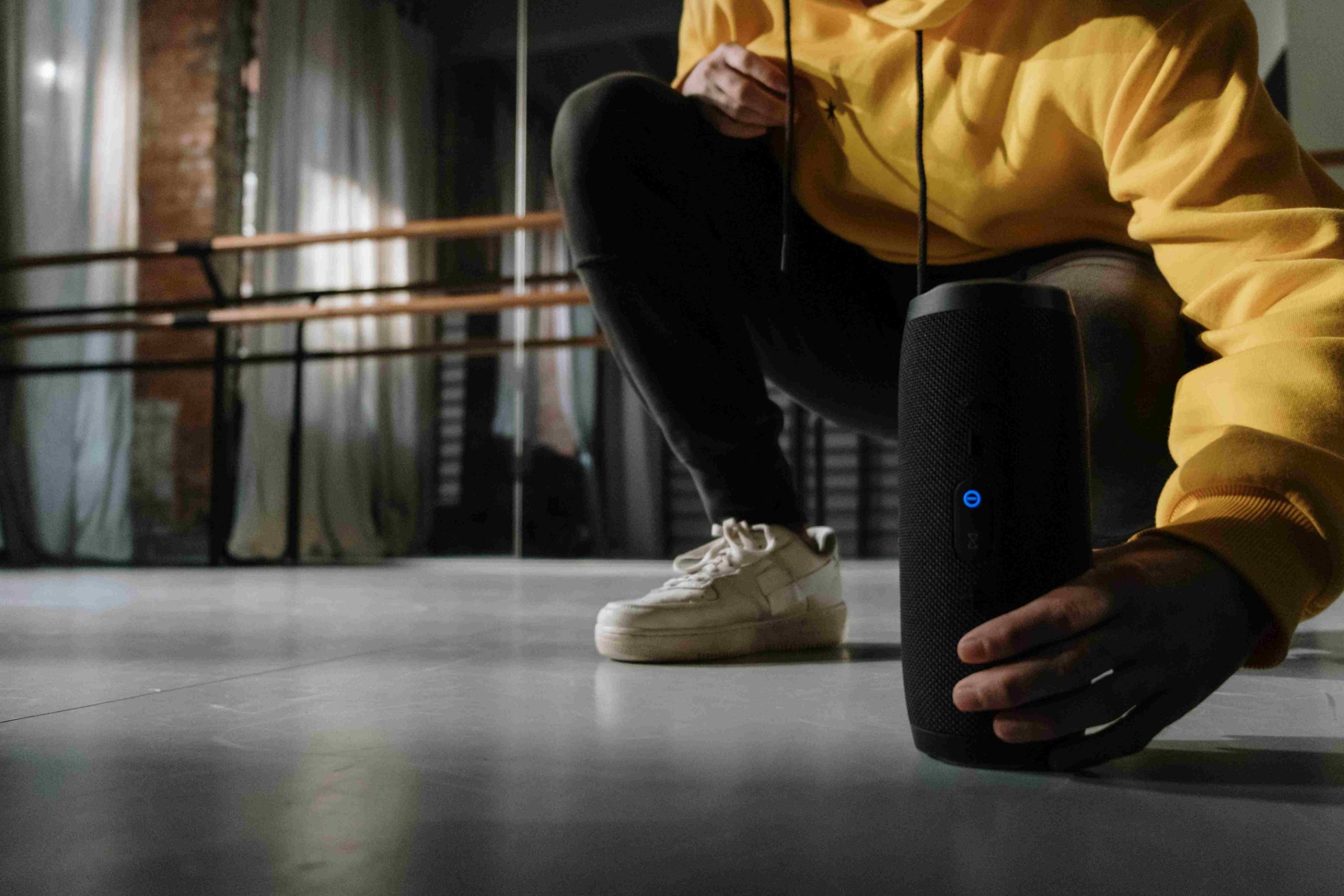 Chico de sudadera amarilla sosteniendo un altavoz portátil negro