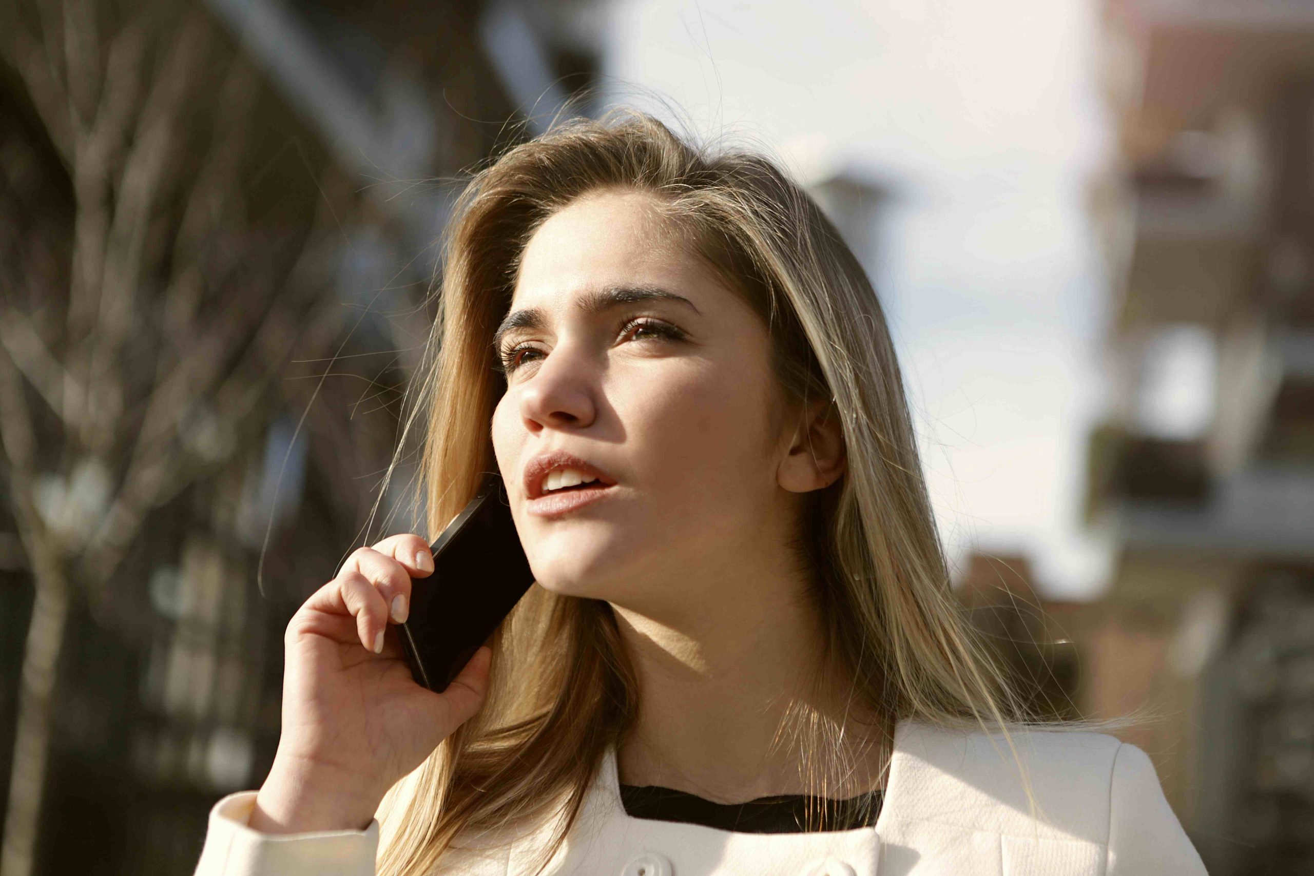 Chica rubia hablando por teléfono en la calle